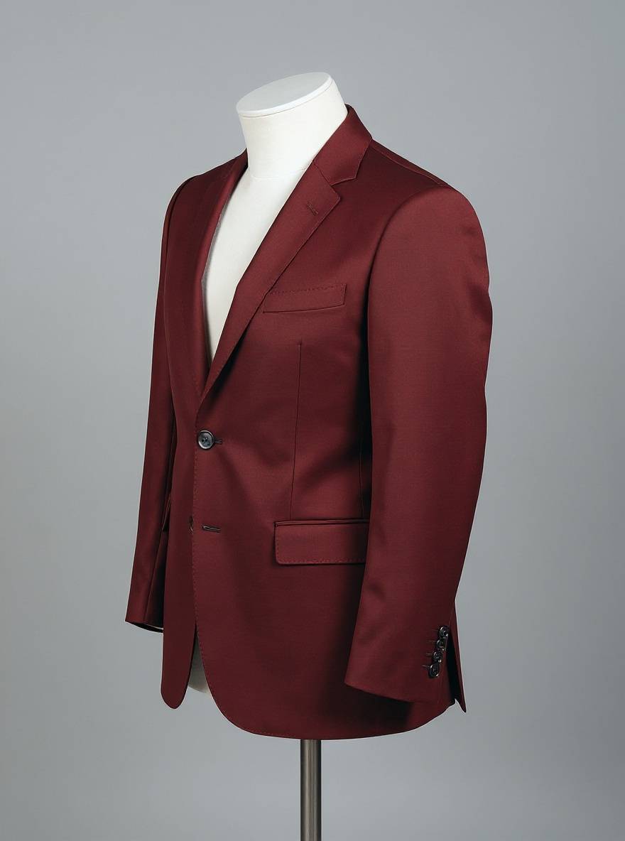 Change only the jacket fabric color from navy blue to warm burgundy. Preserve the exact jacket cut, lapels, seams, fabric weave, buttons, folds, mannequin, camera angle, framing, gray background, lighting, and shadows. Do not alter the white mannequin or add anything. No text.